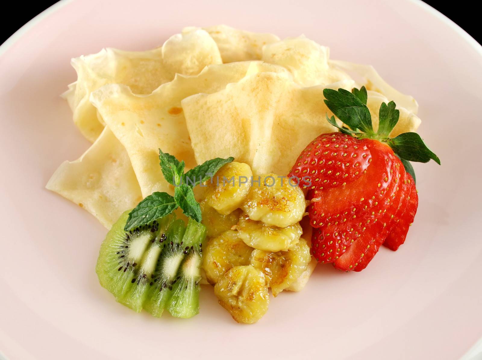 Caramelized banana crepes with strawberries and kiwi fruit.