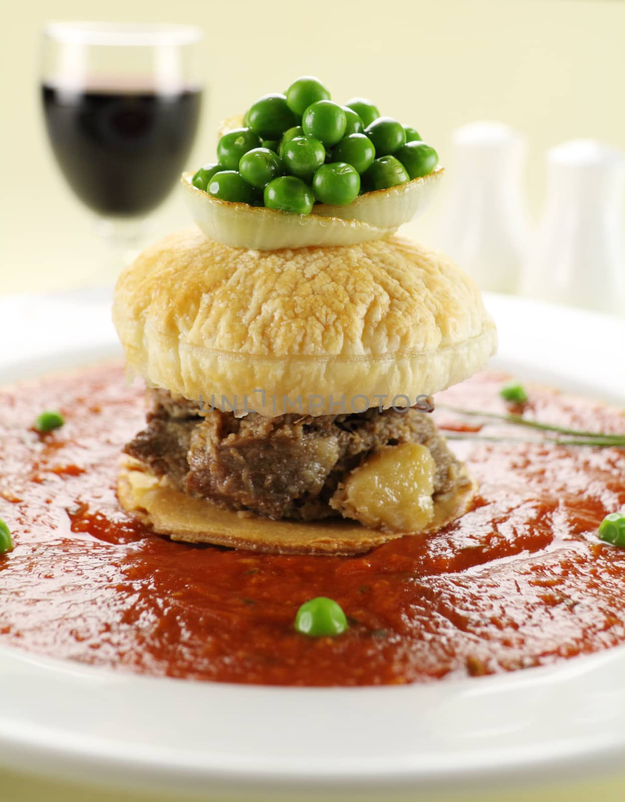 Short beef pie floater with peas floating in tomato sauce.