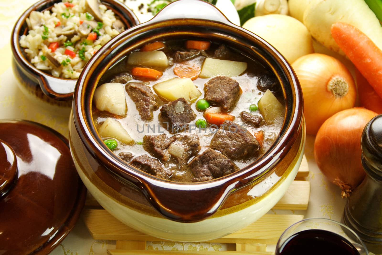 Table setting of freshly baked beef stew with savory rice and seasonal vegetables and herbs.