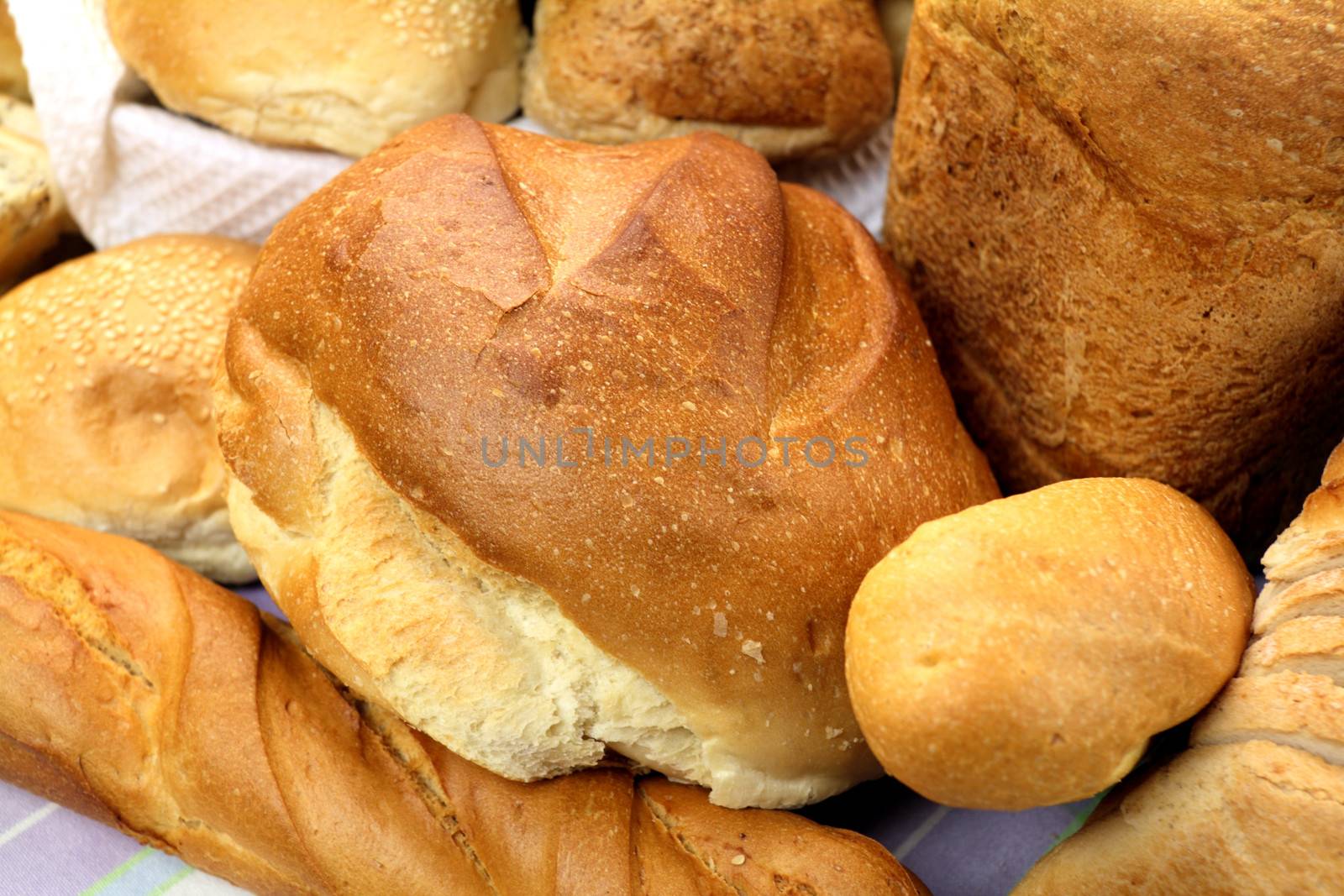 Background of different bread textures with loaves and bread rolls.