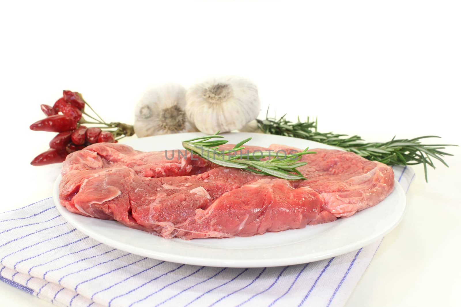 a piece of raw sirloin steak with rosemary and garlic