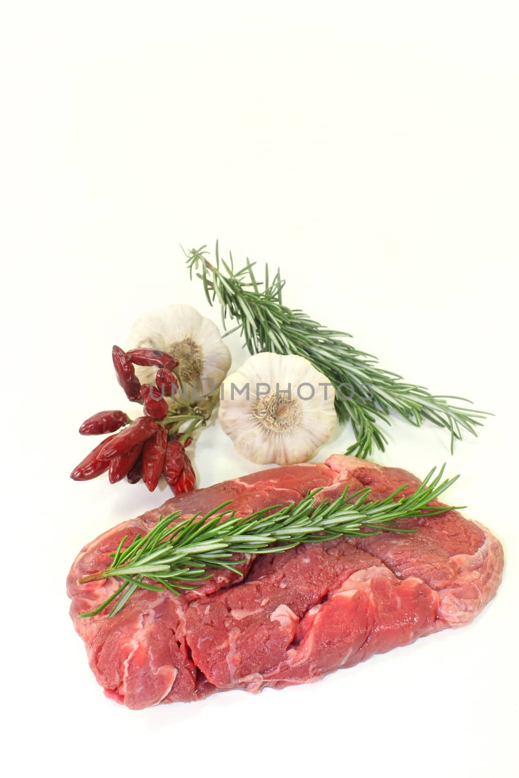 a piece of raw sirloin steak with rosemary and garlic