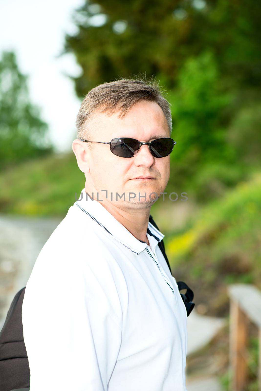 Man with dark sunglasses and white polo shirt