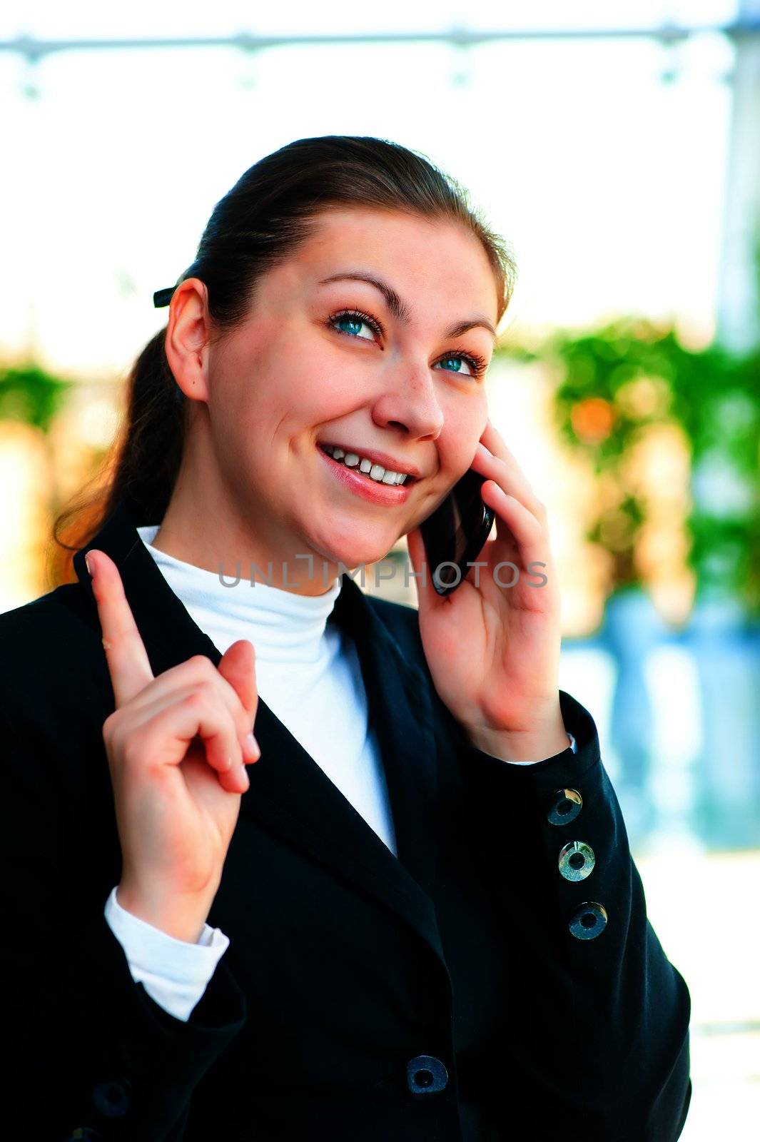 Young happy brunette talking on the phone and shows thumb up. by kosmsos111