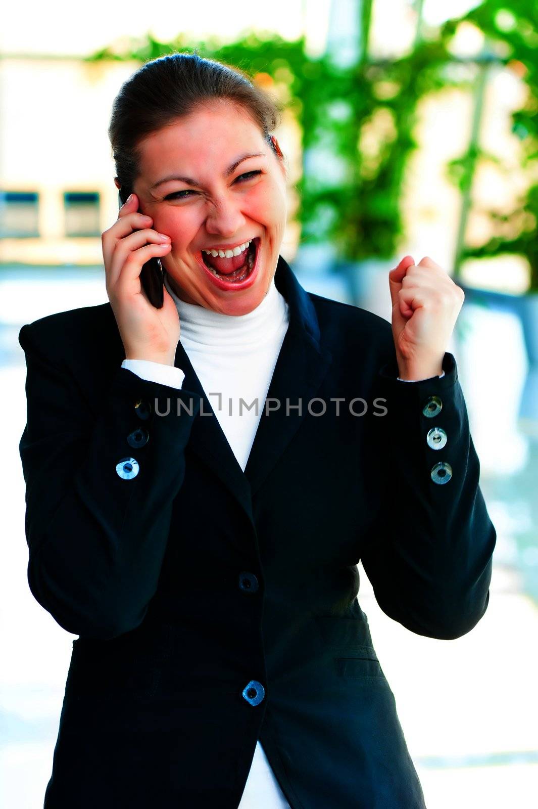 Young brunette enjoys success with the phone on office background by kosmsos111