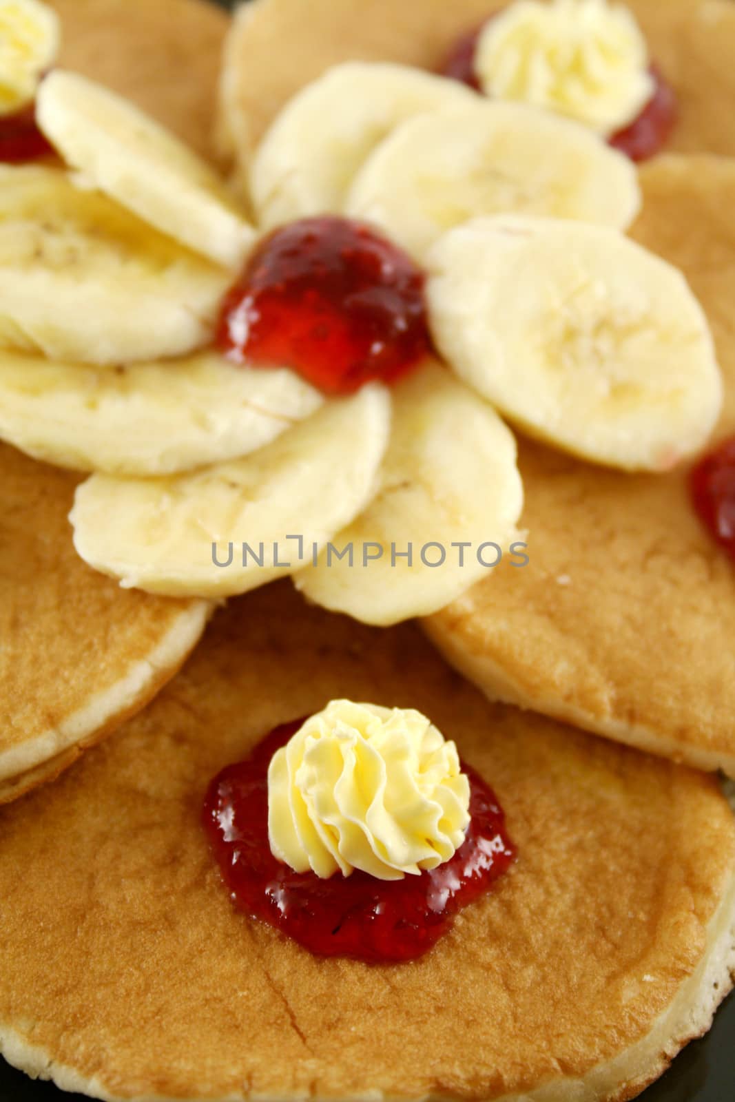 Delicious pancakes with butter swirls and strawberry jam with banana.