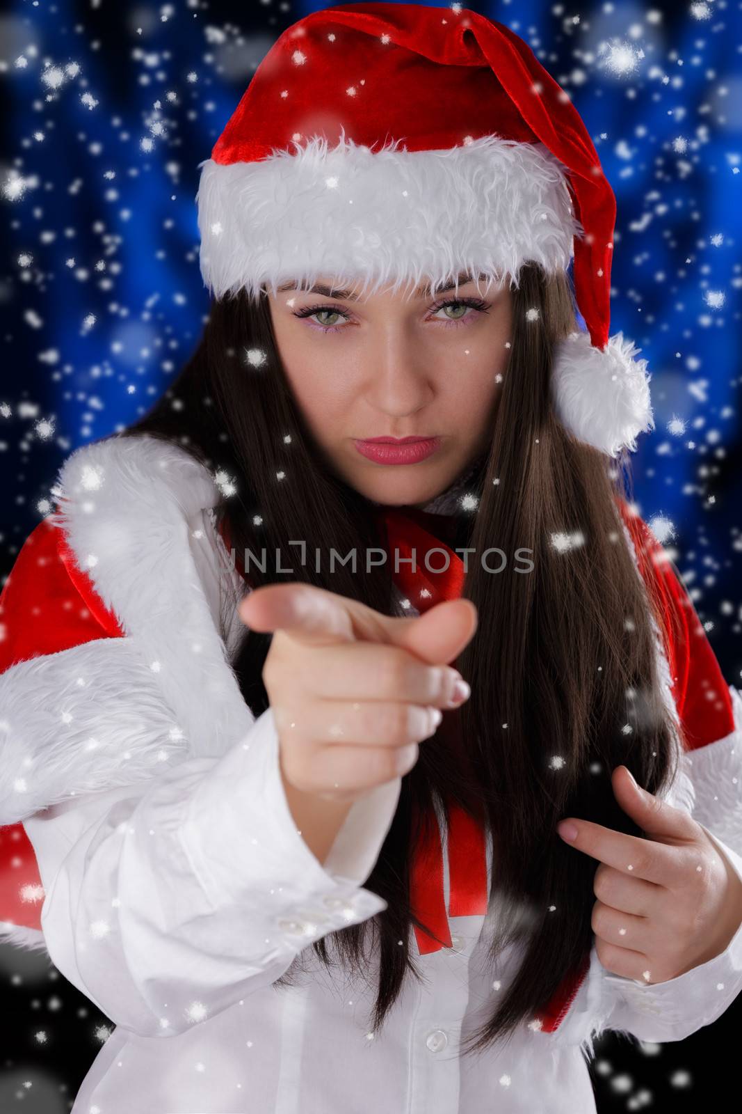 Beautiful girl pointing at the viewer with snow falling around her.