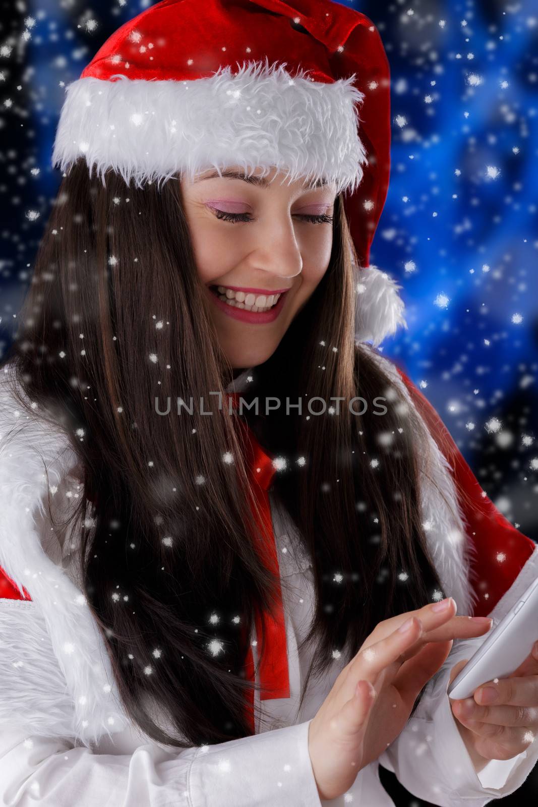 Beautiful girl interacting with a smart phone with snow falling around her.