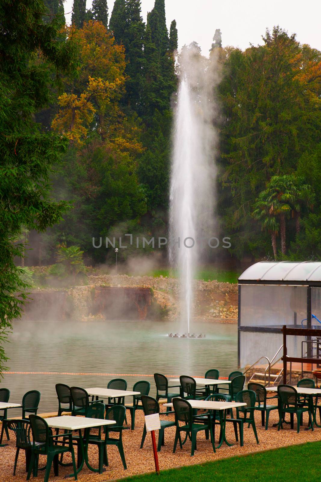 Green tables and chairs near a thermal lake 