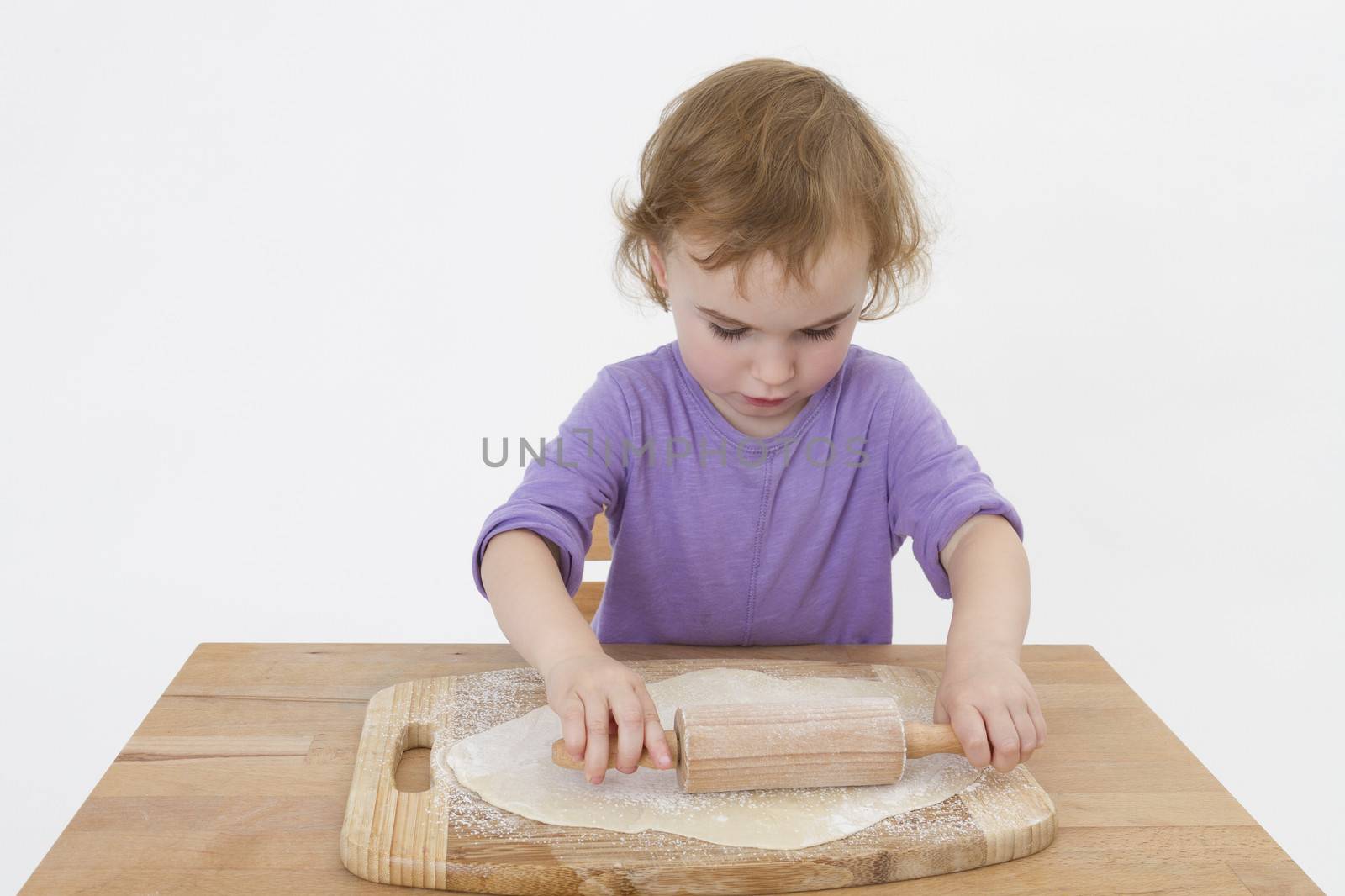 cute curly child rolling out dough by gewoldi