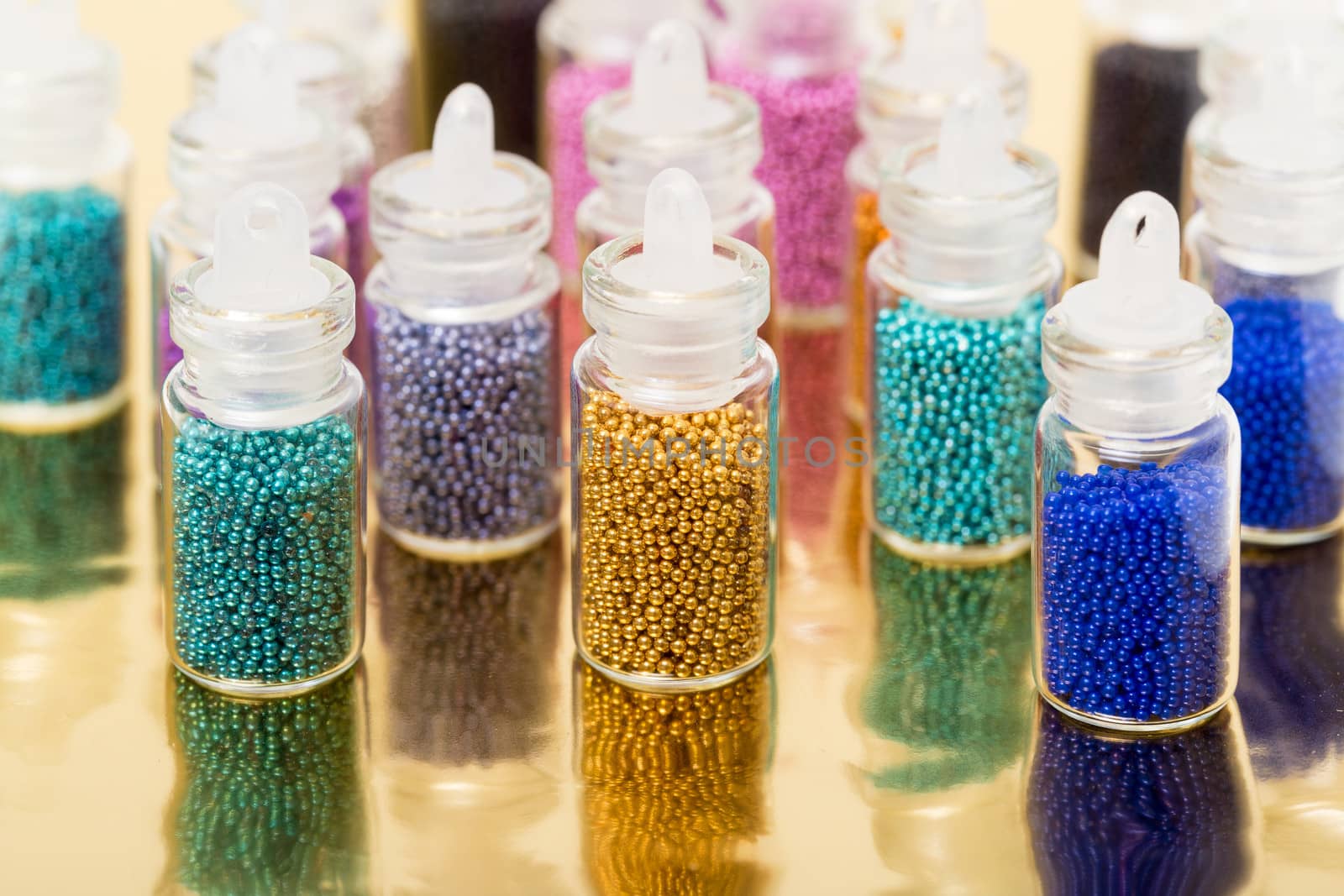 Small Glass Jars filled with Balls of Bead, on golden background