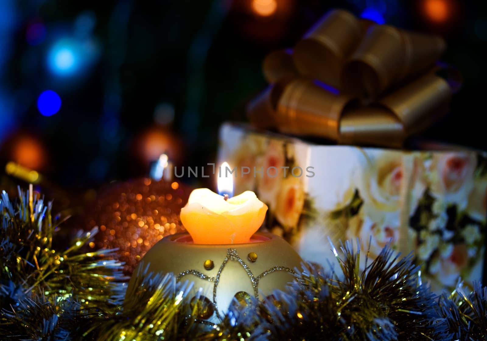 Candle on the background of the Christmas tree and gifts