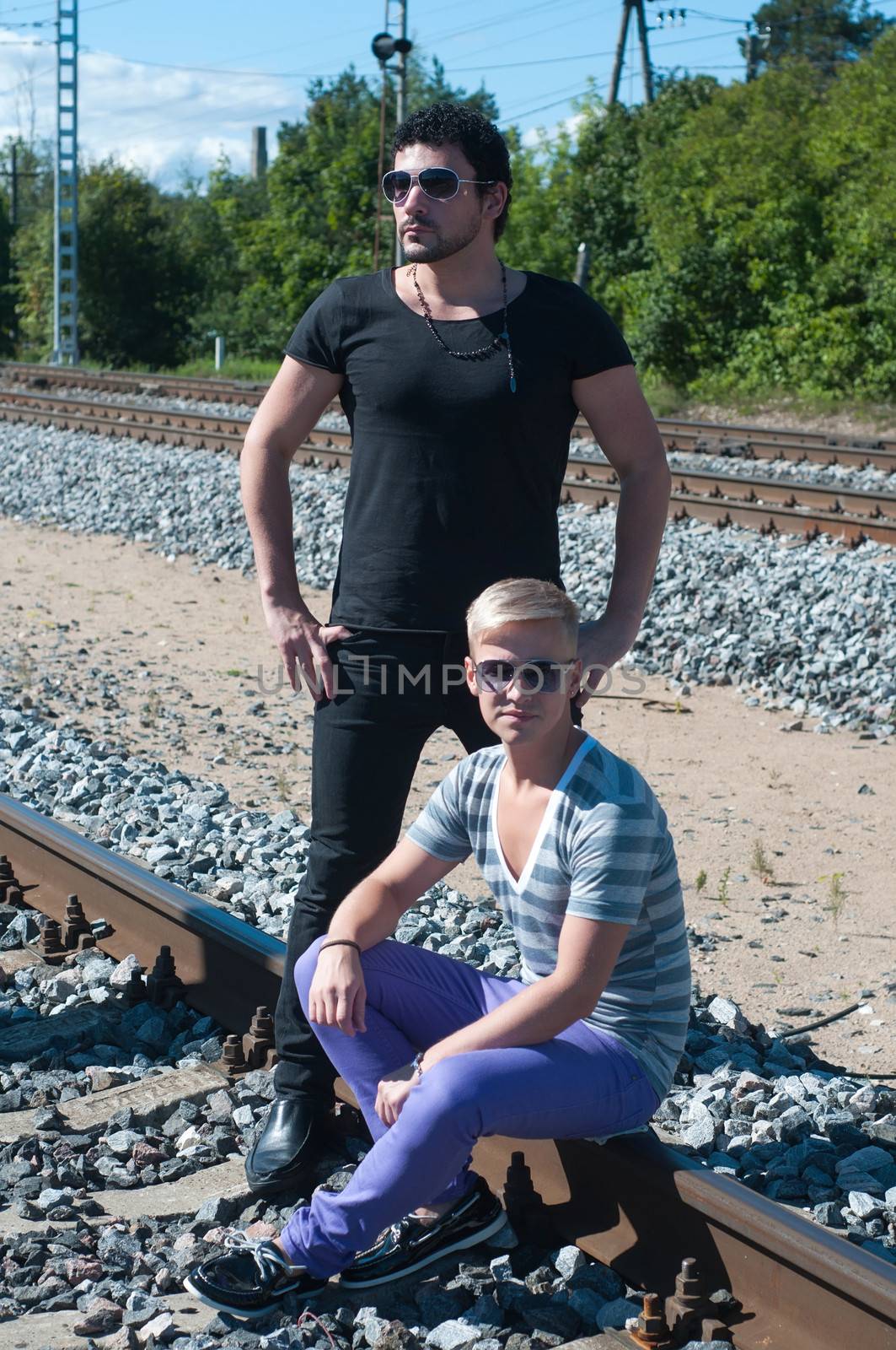 Shot of two men on train tracks, focus on man in black