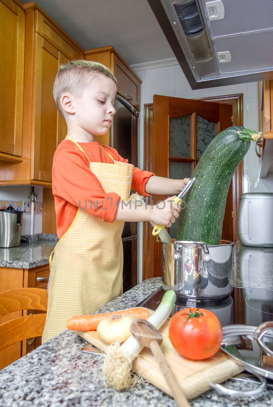Cute child chef cooking big zucchini in a pot by doble.d