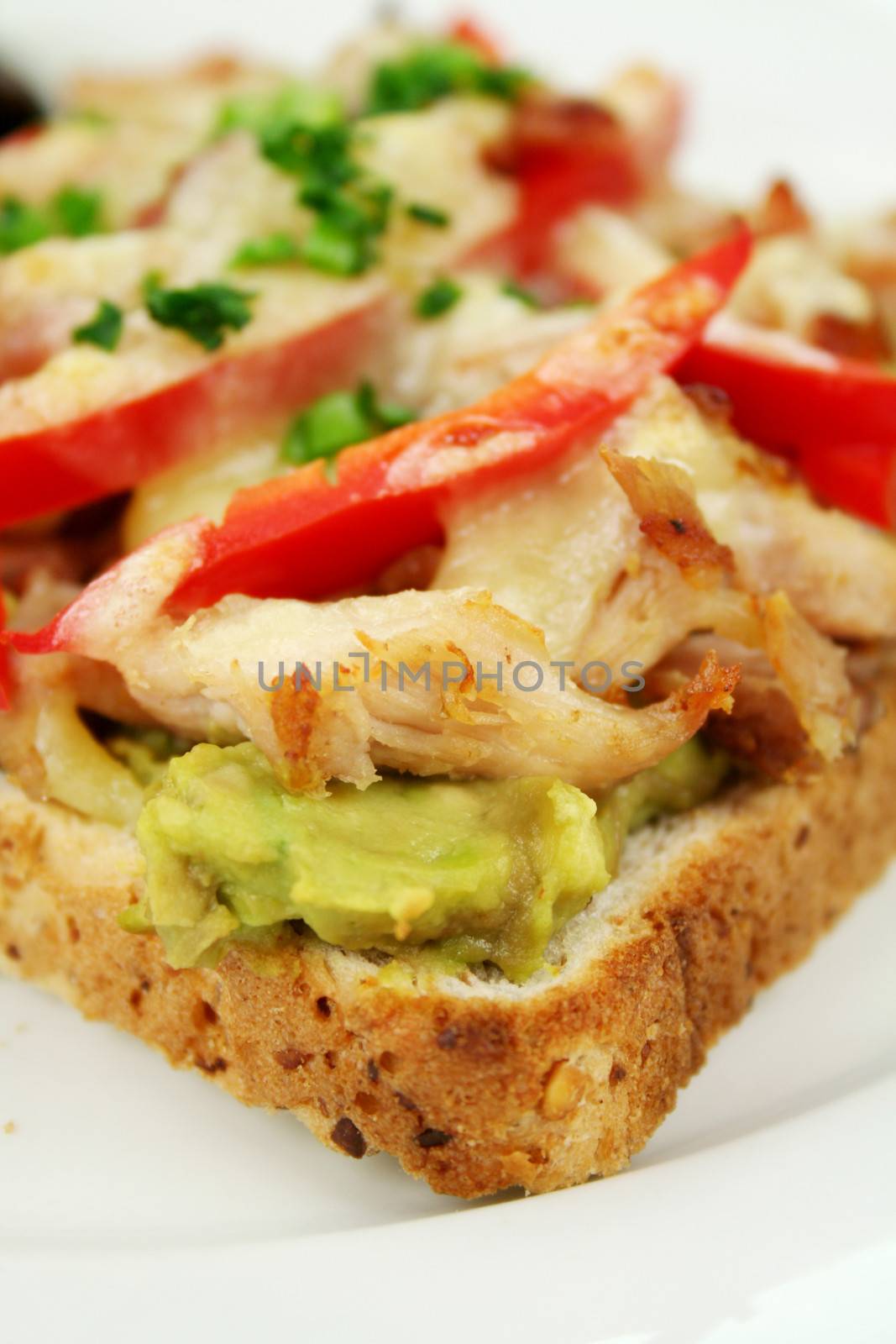 Grilled open chicken sandwich with avocado, peppers and cheese with a side salad.