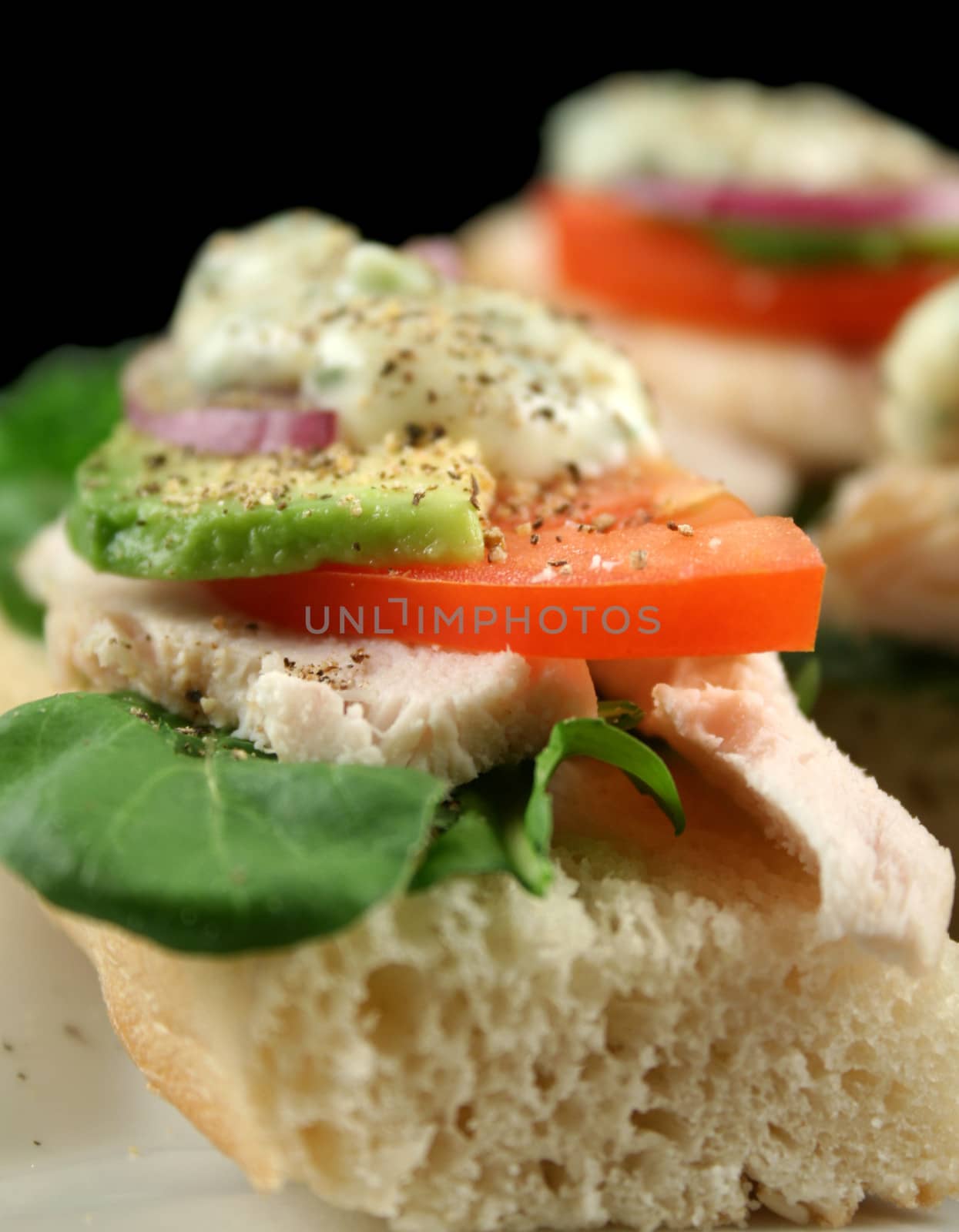 Fresh open chicken finger sandwiches with avocado red onion and mayo with lettuce