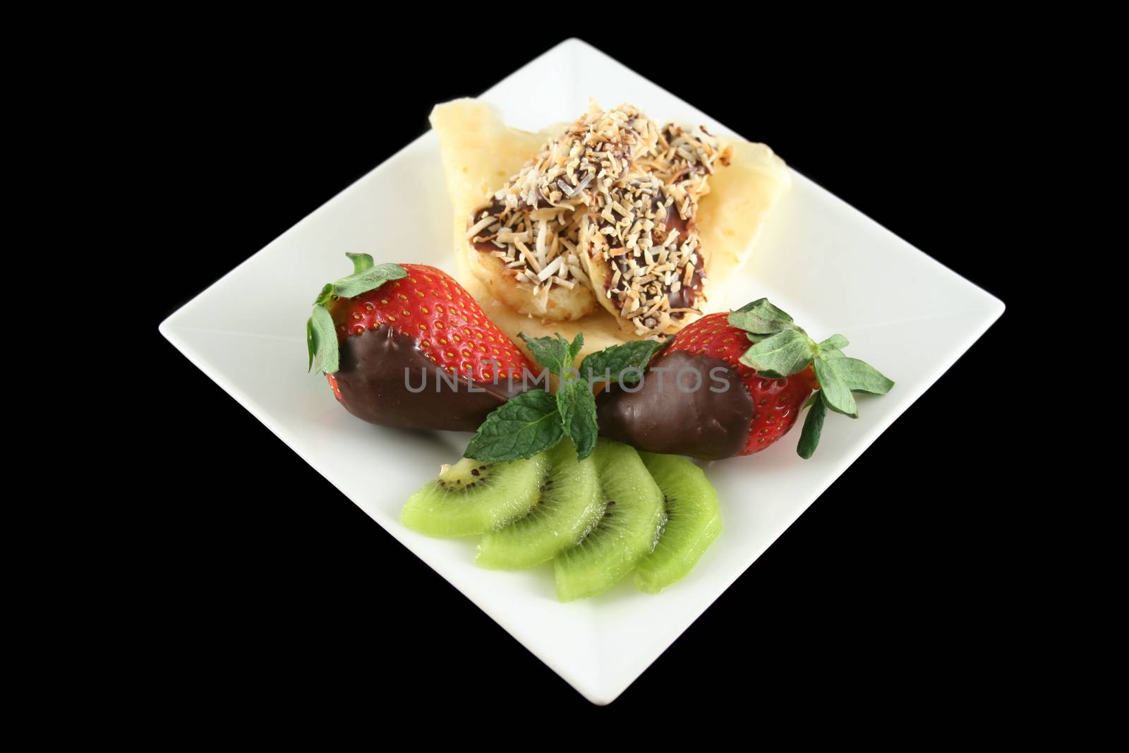 Pancake topped with chocolate and coconut coated bananas with strawberries and kiwi fruit.