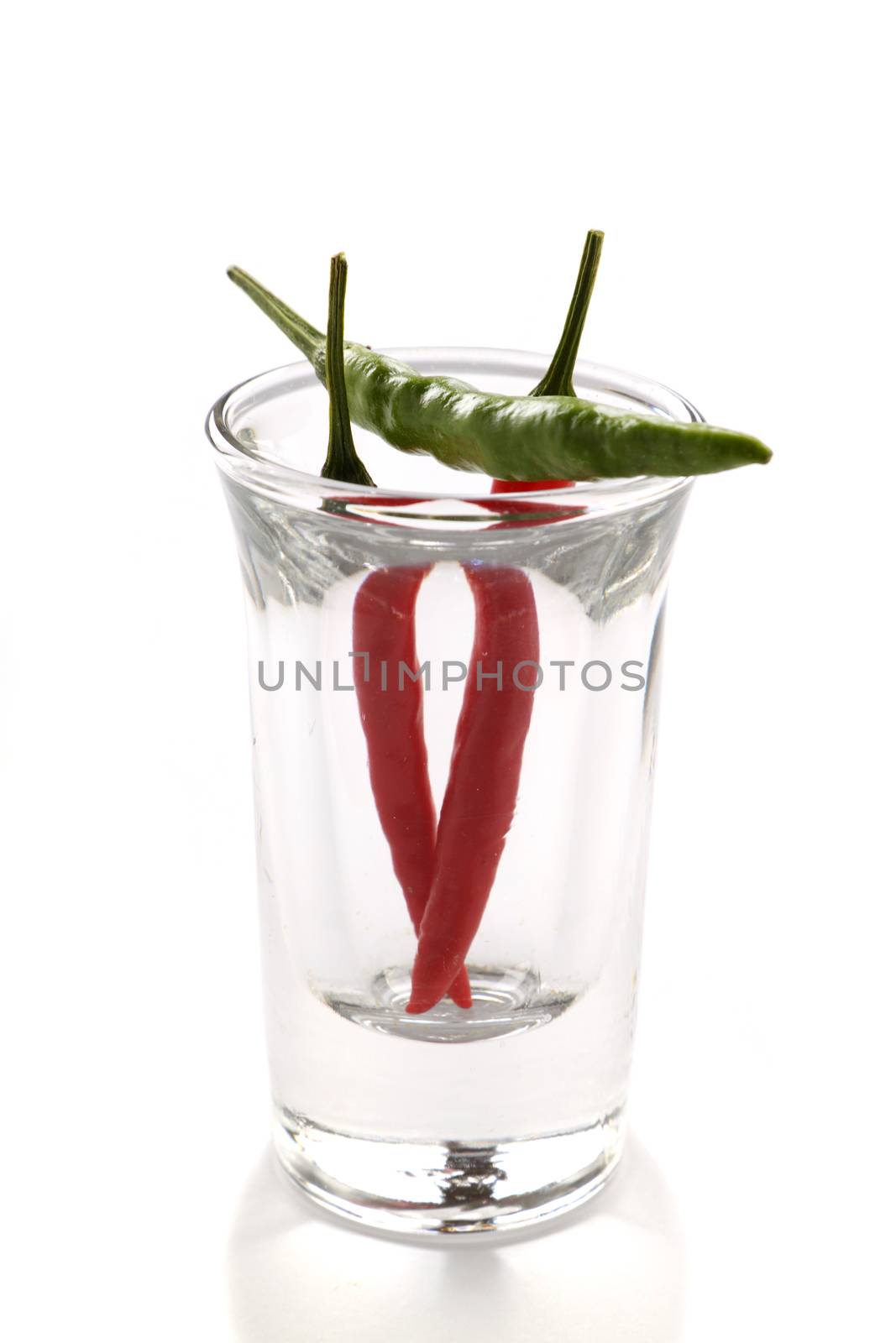 Three red and green hot chillies in a shot glass.