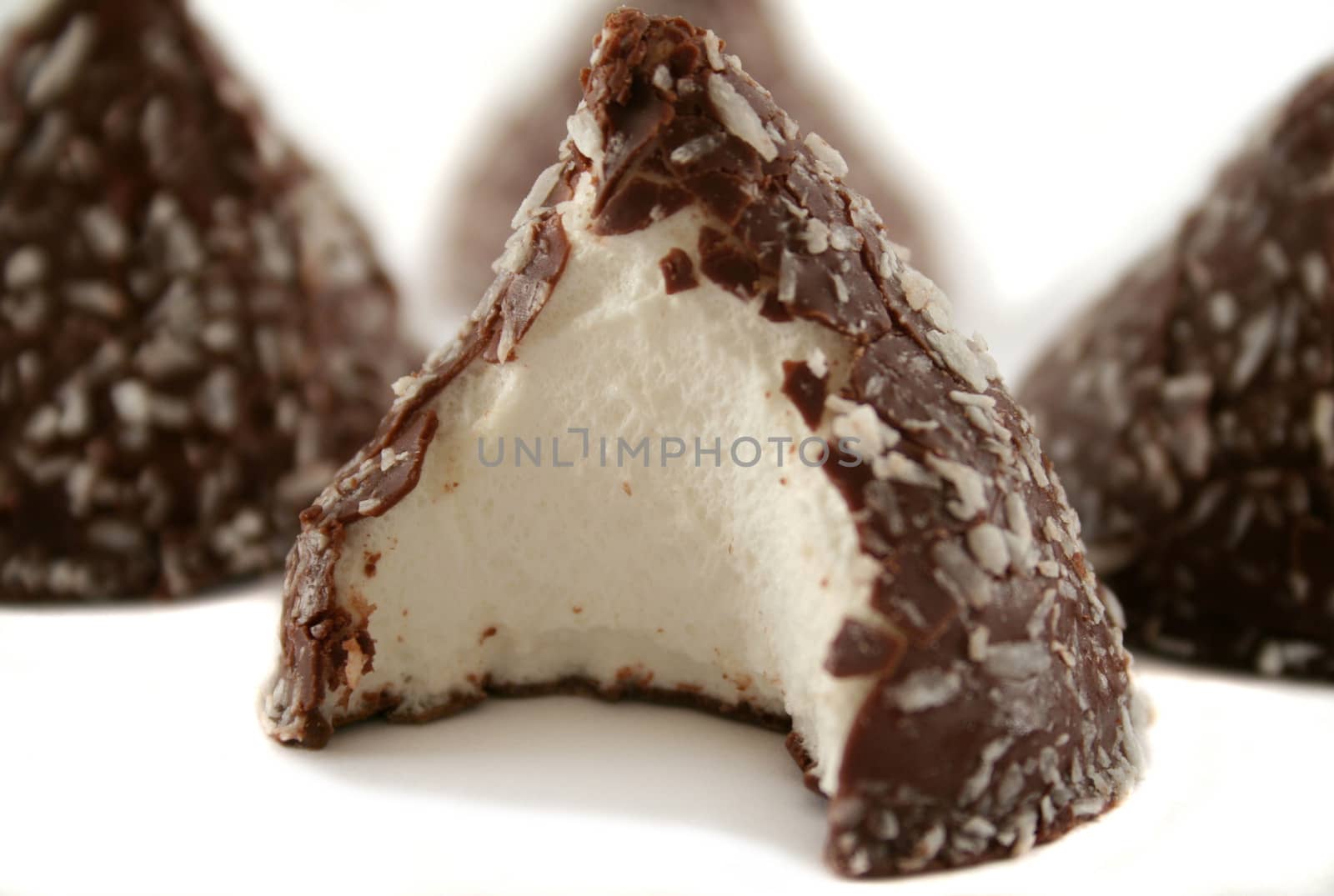 Chocolate and coconut covered marshmallow cones with a bite out of one.