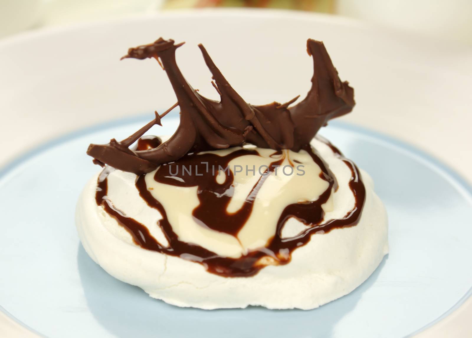 A fresh baked meringue with a chocolate sculpture sitting on top.