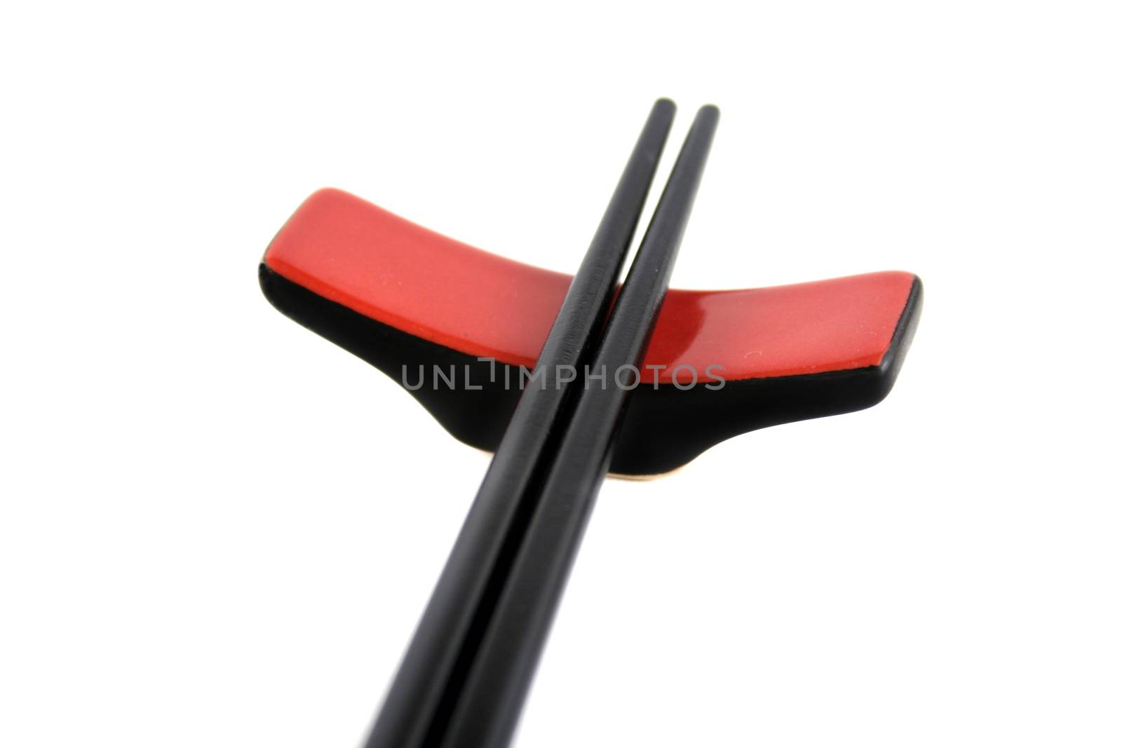 Black chopsticks sitting on a rest.