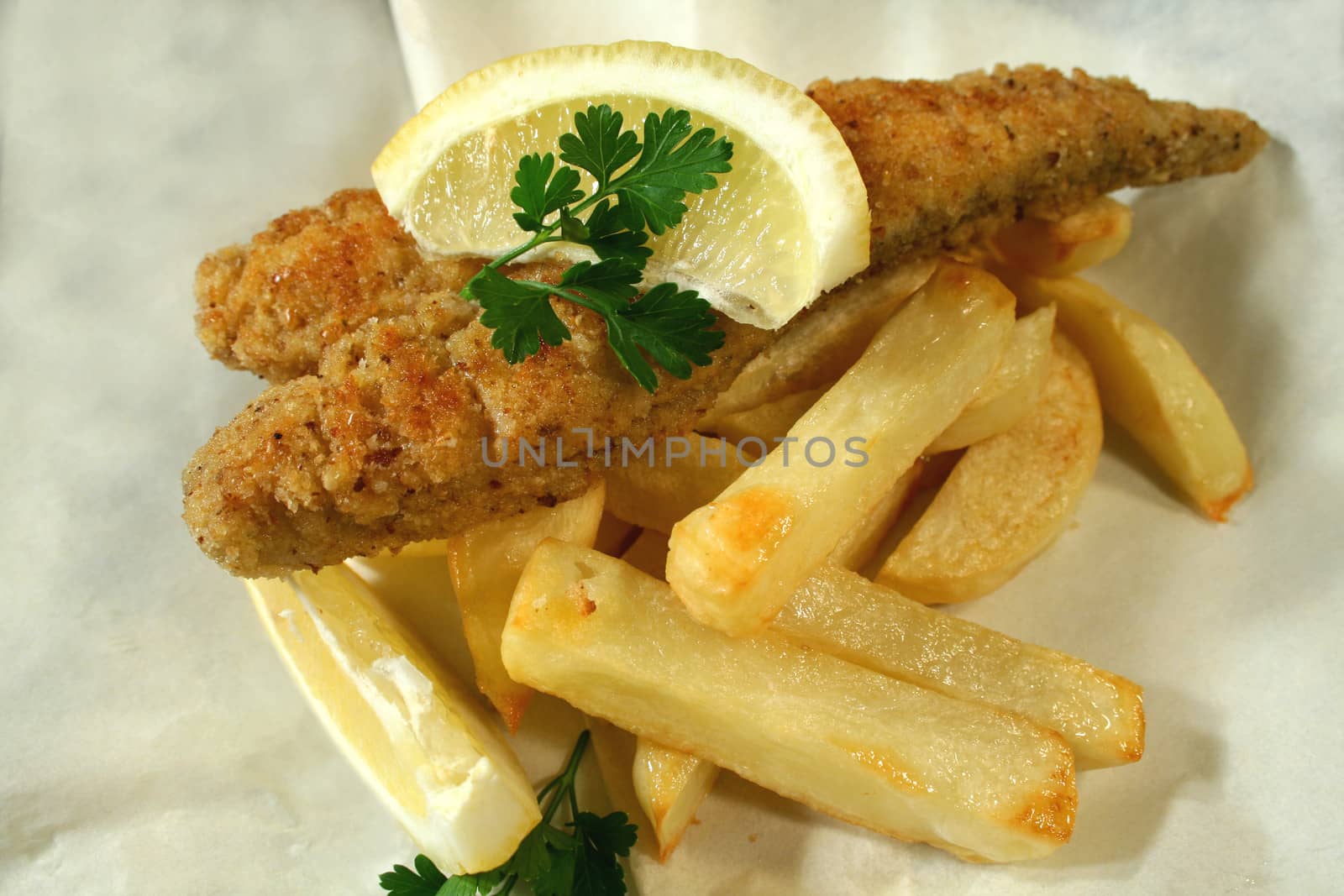 Classic fish and chips meal of crumbed whiting fillet with chips in paper.