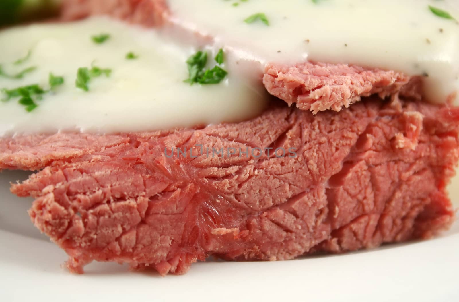 Delicious sliced corn beef with white sauce and vegetables.