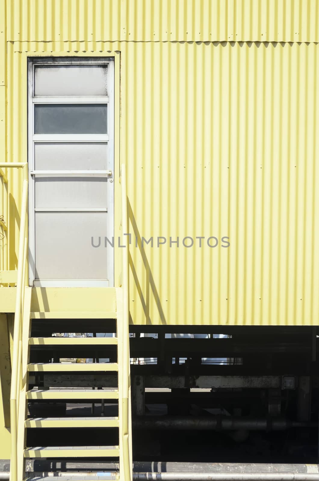 Yellow industrial stairs and galvanized iron wall