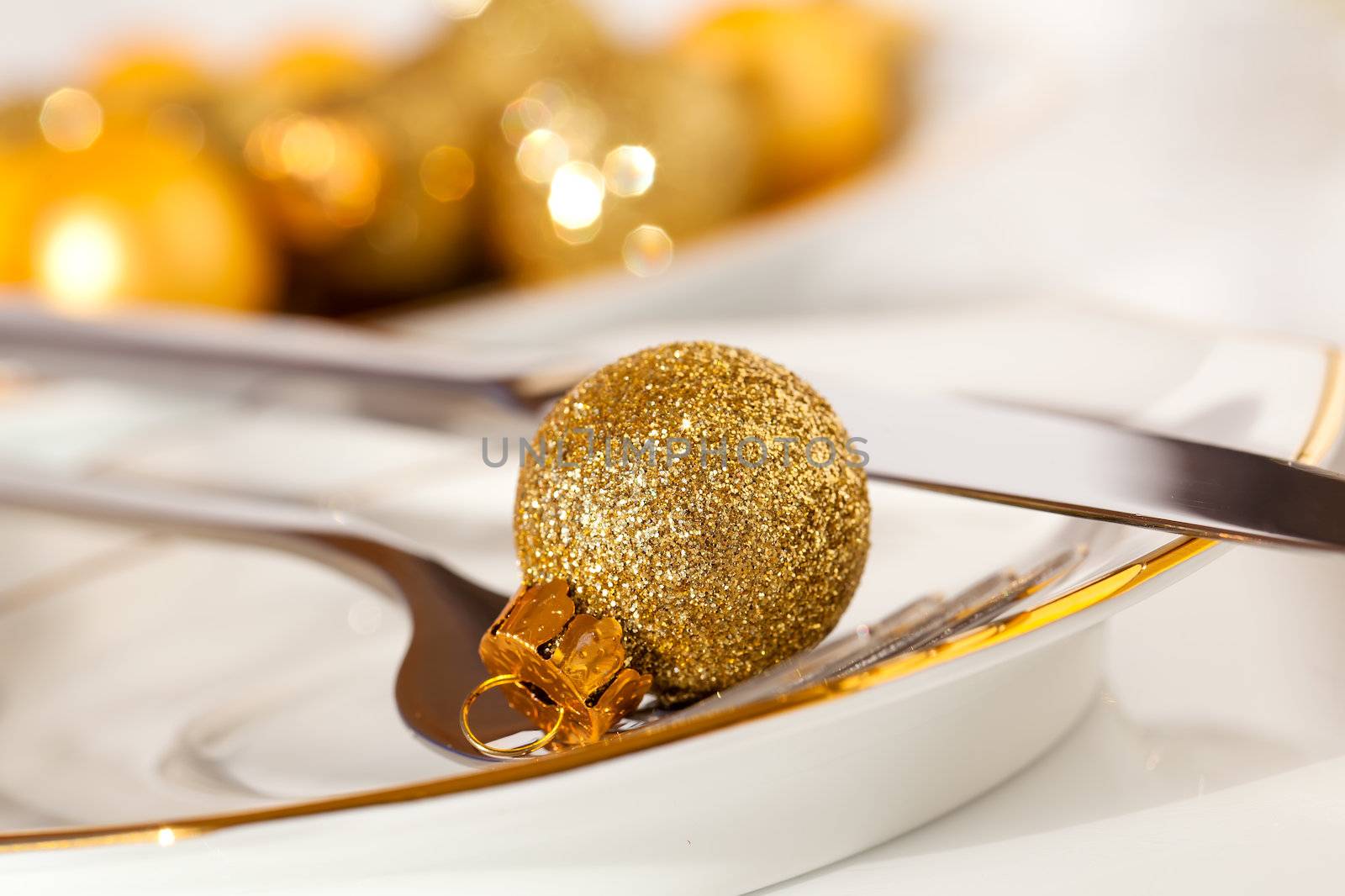 silver cutlery decorated with a golden Christmas bauble