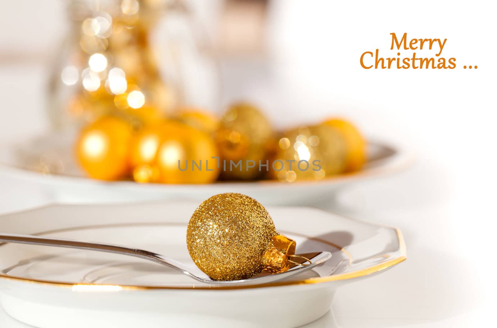 silver cutlery decorated with a golden Christmas bauble, with copy space