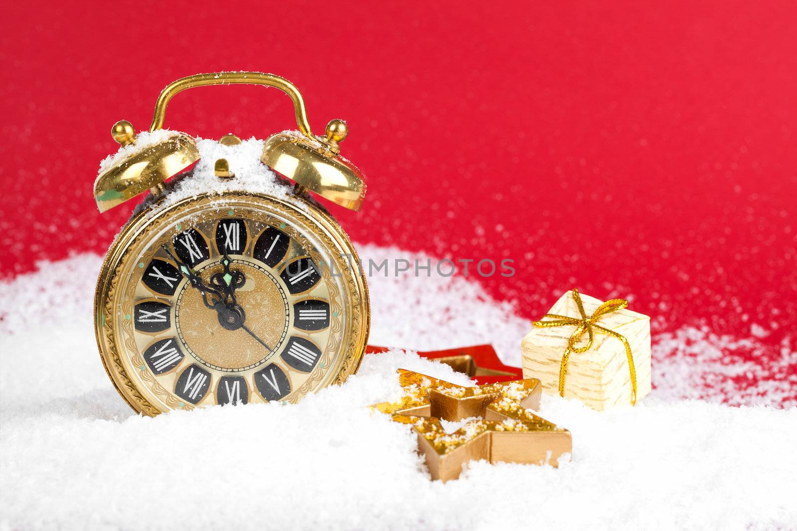 vintage christmas decoration golden star and antique golden clock in snow on red background