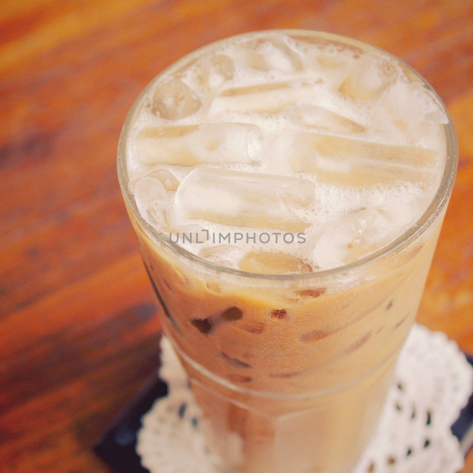 Iced coffee on wooden table with retro filter effect