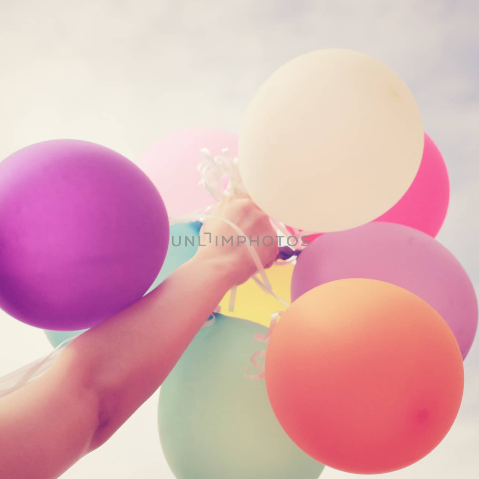 Hand holding multicolored balloons with retro filter effect by nuchylee