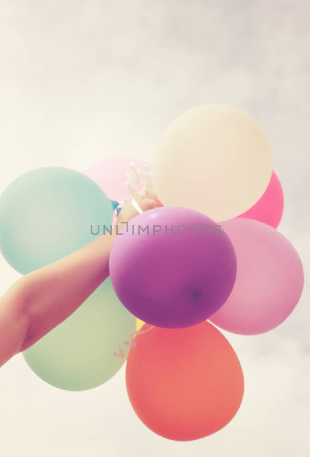 Hand holding multicolored balloons with retro filter effect by nuchylee