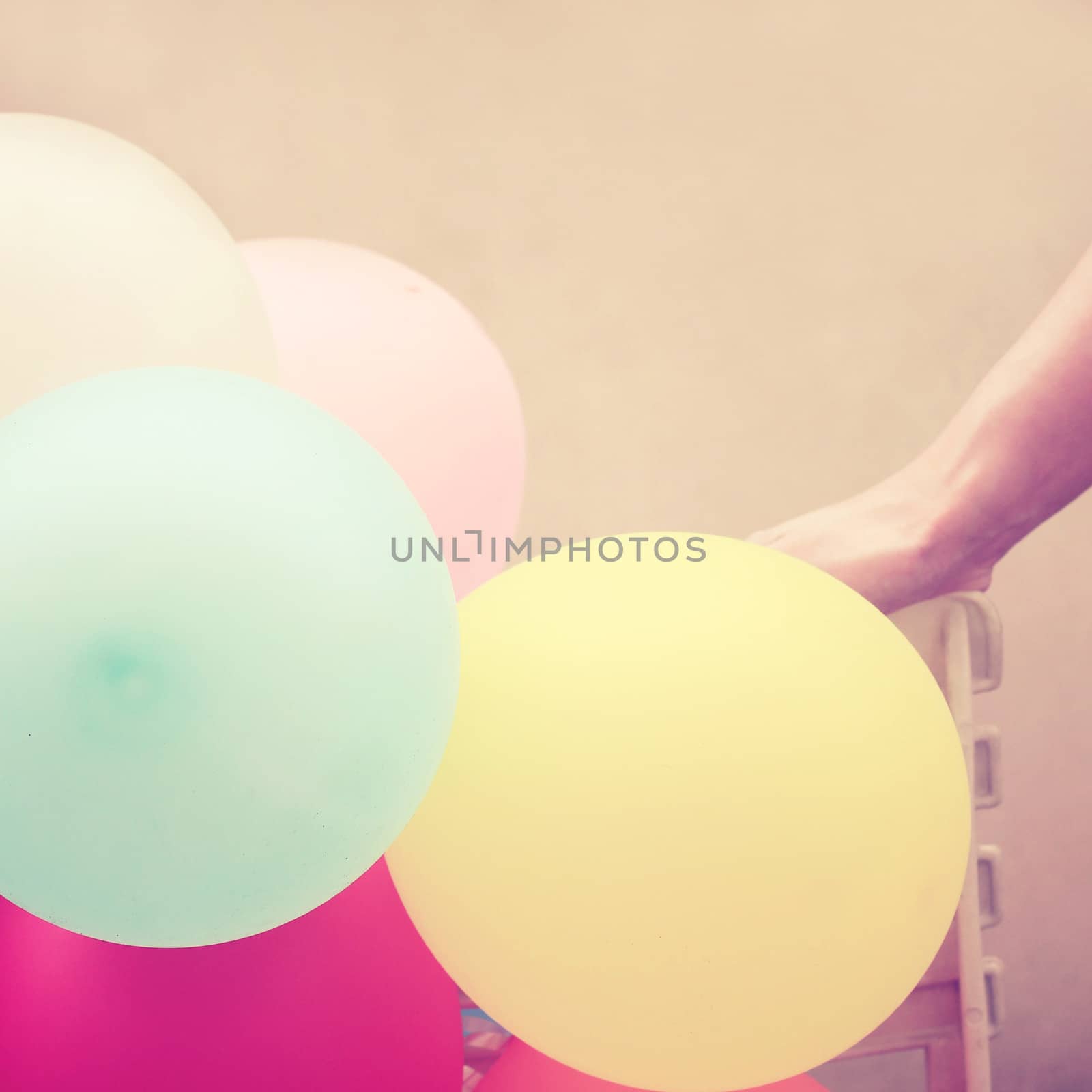 Colorful balloons with hand on chair, retro filter effect