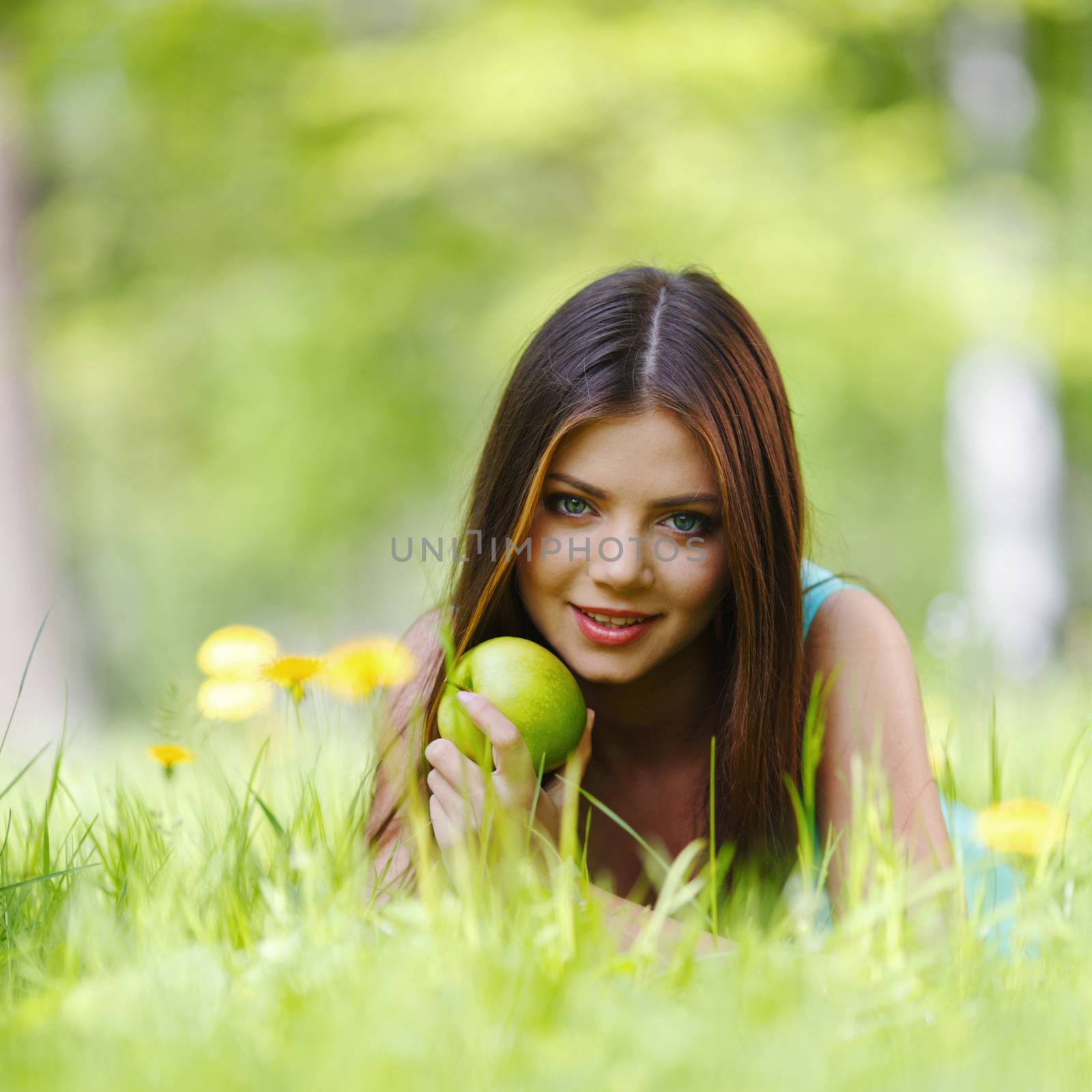 Woman with apple laying on green grass