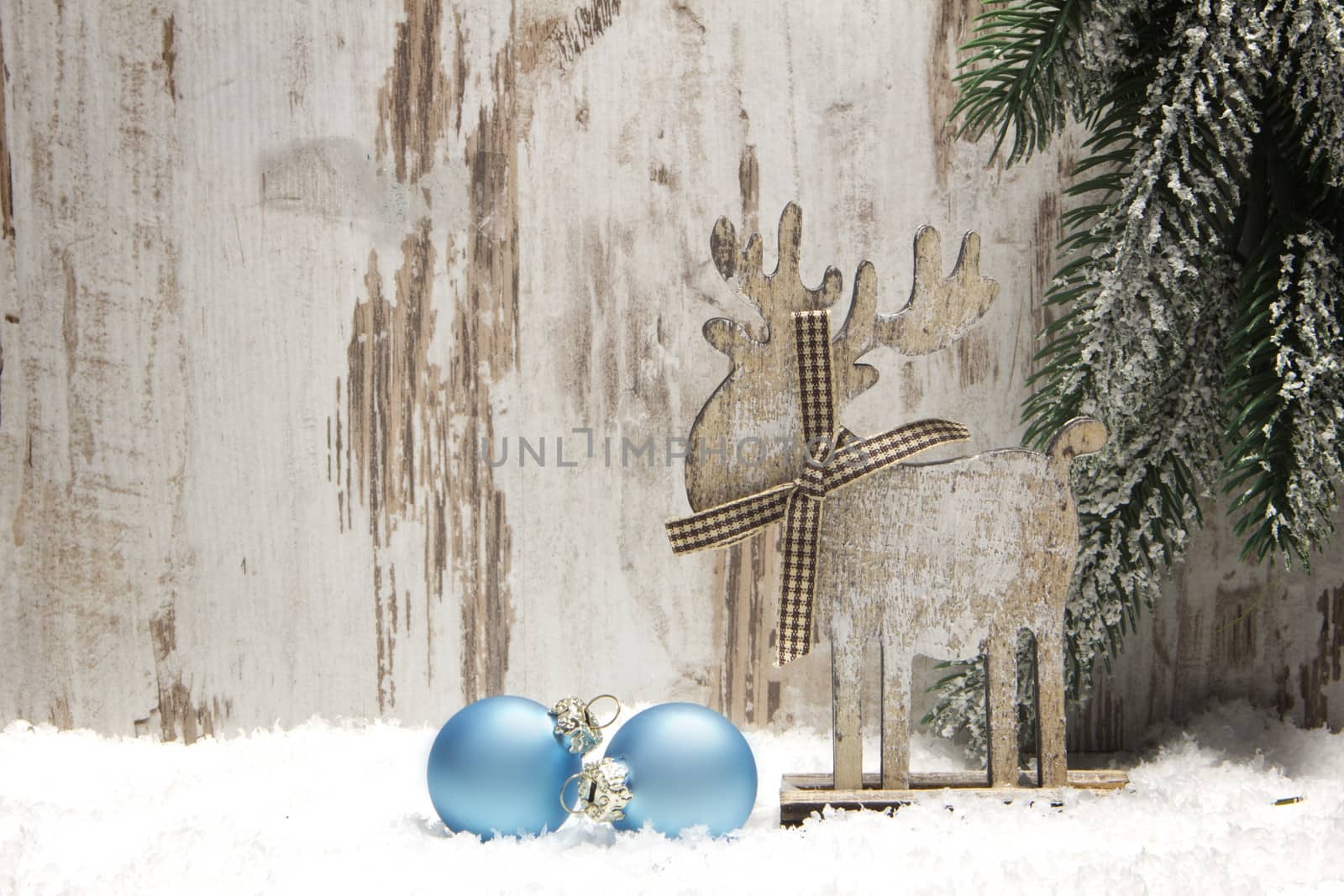 christmas decoration with wood background, snow, elk, christmas baubles blue and fir branch 