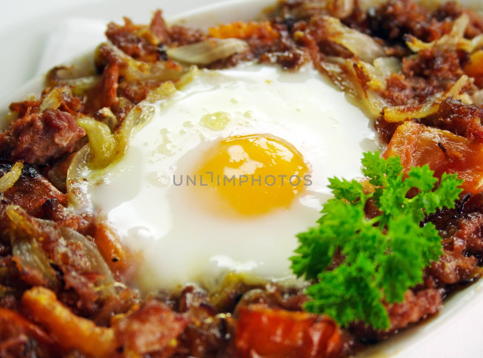 Baked corned beef hash with egg, tomato and onion with parsley.