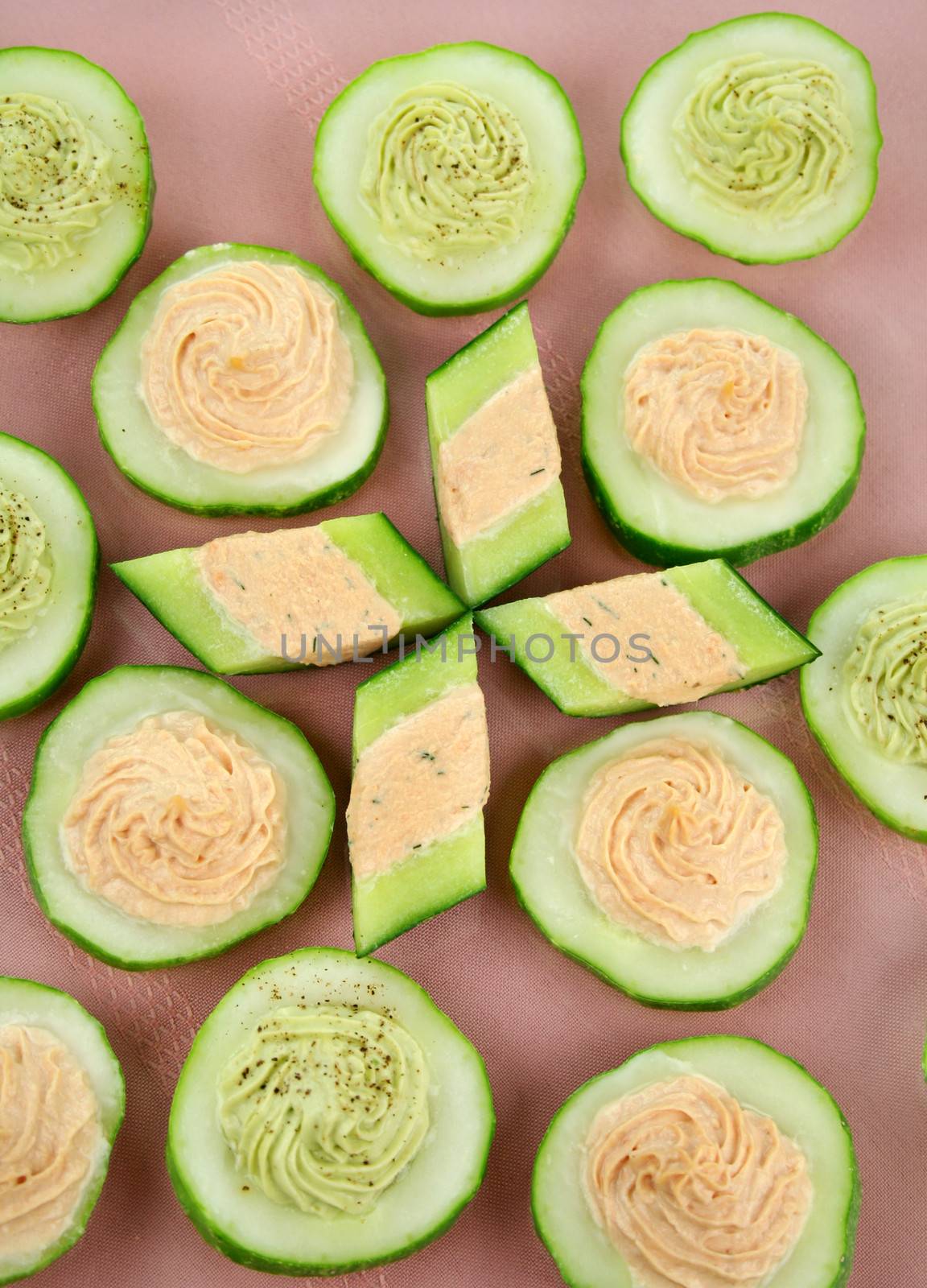 Delicious cucumber rounds with avocado and salmon with cream cheese.