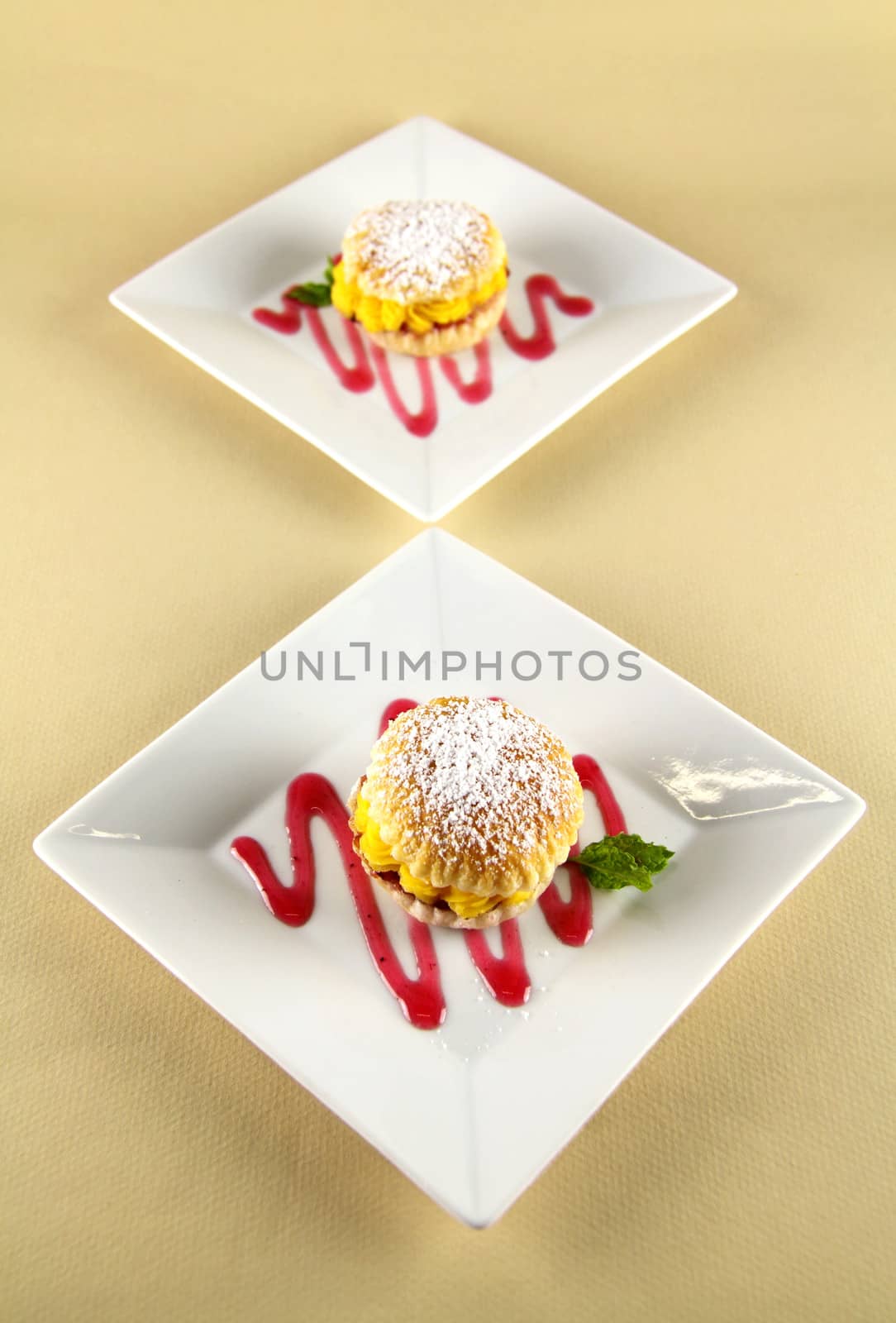 Custard pastry cakes in a line diagonally on plates.