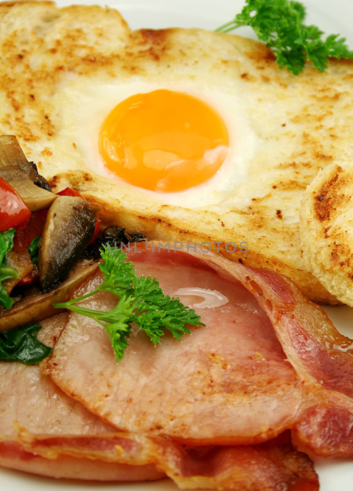 Egg embedded in toast with bacon, mushrooms, spinach and tomatoes.