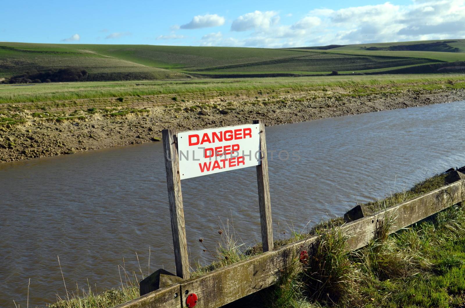 Along Cuckmere river in Sussex, England a sign informing to be careful because of deep water.