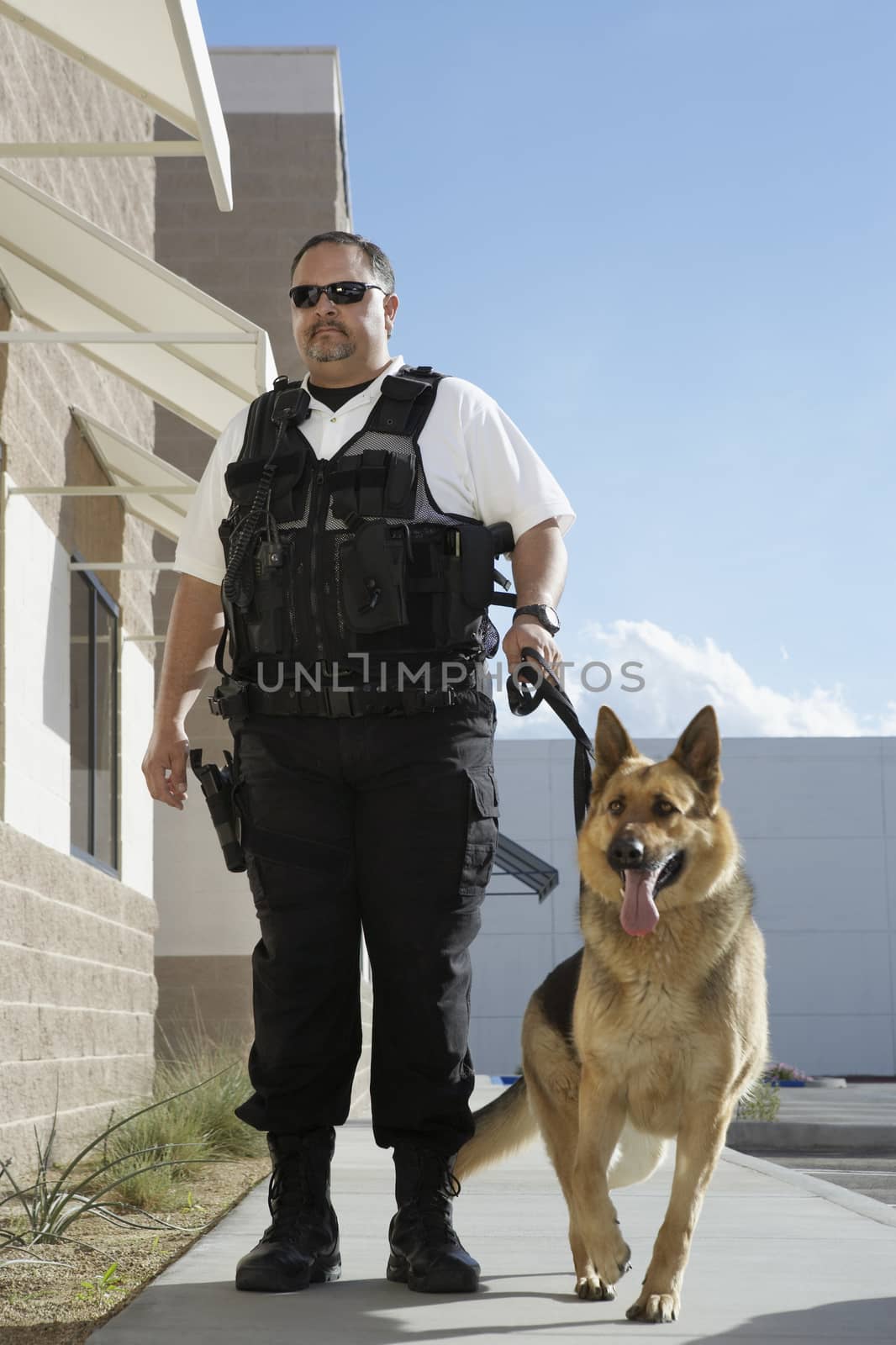 Full length of a security guard with trained dog on patrol by moodboard
