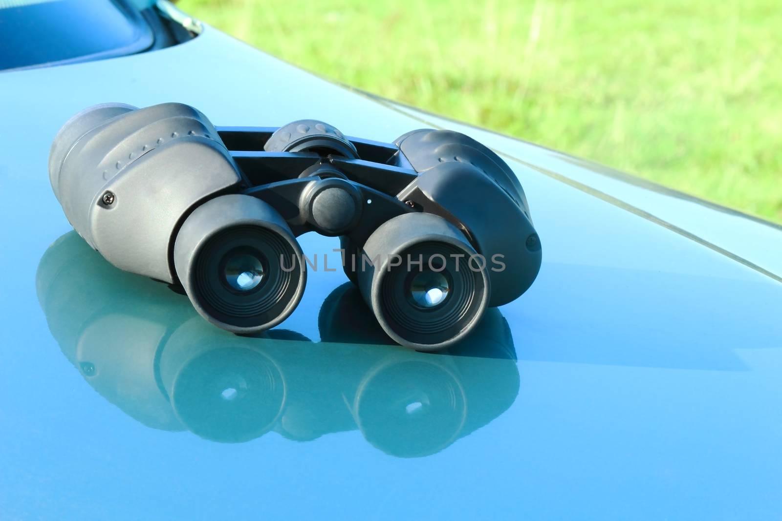 Binoculars lying on the car hood. by georgina198