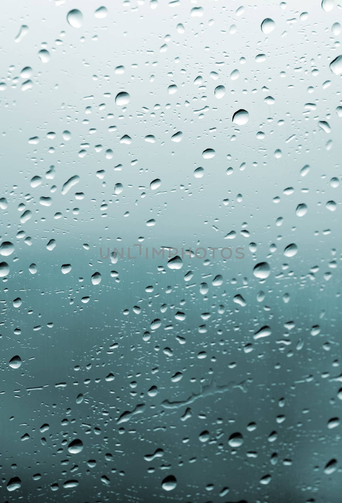 Raindrops on the glass surface. Blue wallpaper                               