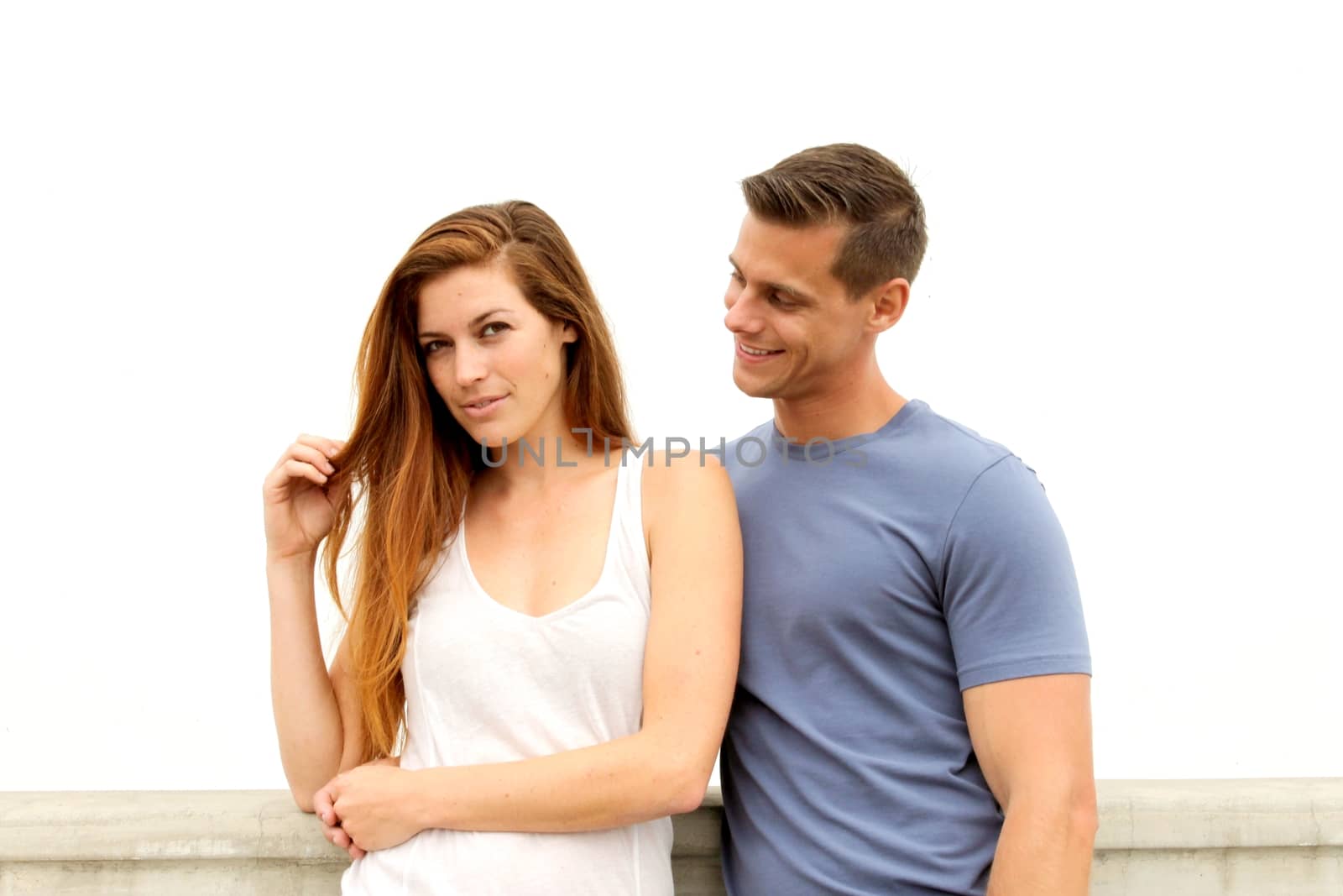 Young couple standing in front of a white wall.