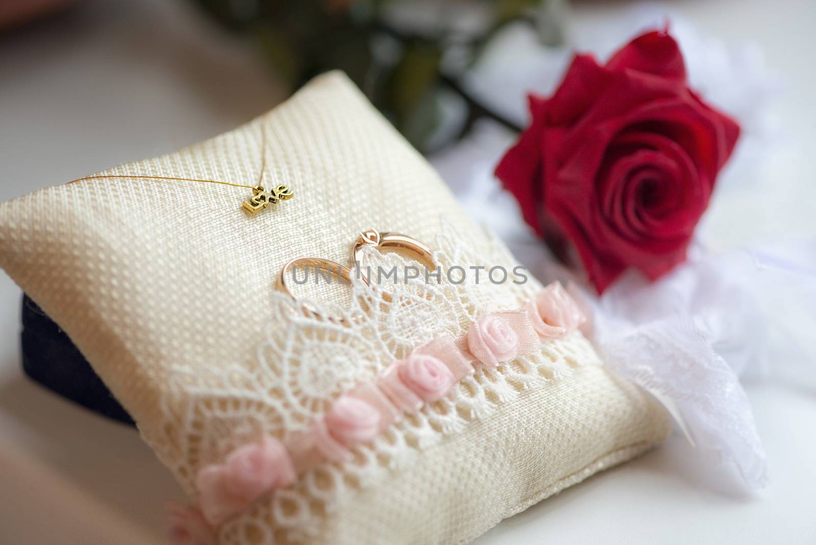 wedding rings on the pad and red rose