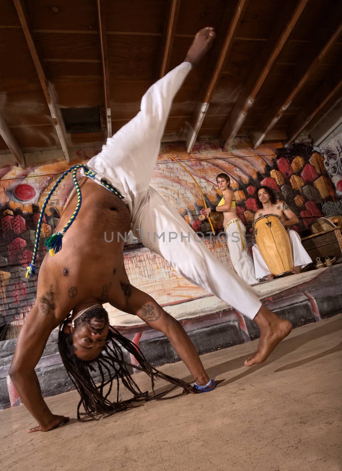 Capoeira man performing a cartwheel flip indoors