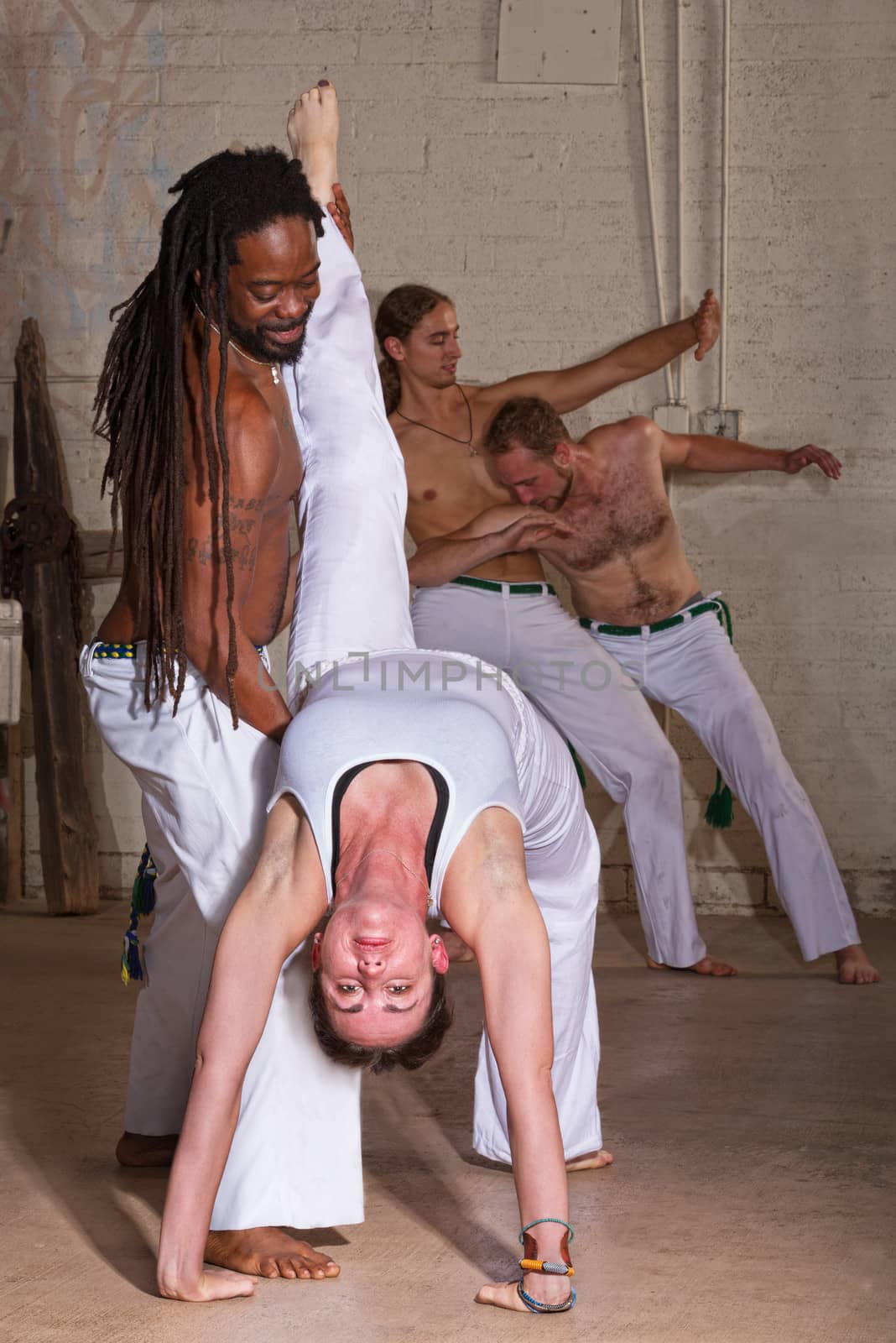 Capoeira instructor holding student that is bending backwards