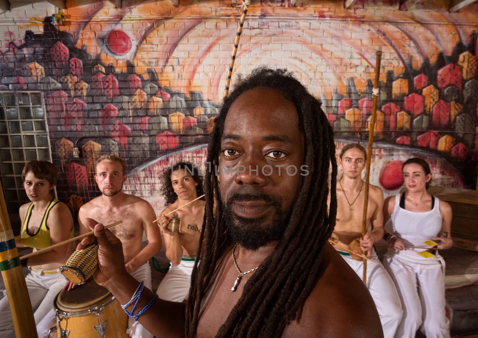 Handsome African capoeira master with students playing music
